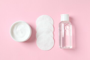 Micellar cleansing water, cream and cotton pads on a color background, top view. Flat lay.