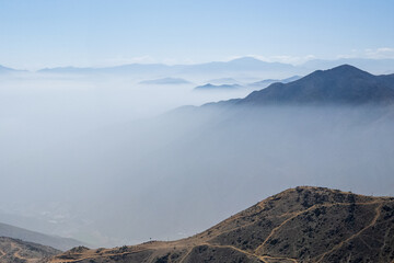 The sky is hazy and the mountains are covered in clouds