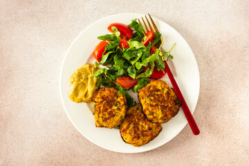 Savor a balanced and appetizing breakfast of crispy zucchini pancakes, complemented by fresh lettuce and tomatoes for a healthy, vibrant, and flavorful morning meal