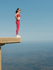 Sporty woman standing on top of a high concrete building, living on the edge concept