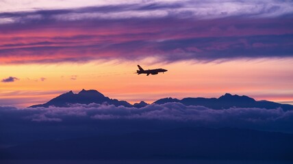 Naklejka premium Jet soaring above mountains with evening clouds in the distance