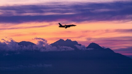 Jet soaring above mountains with evening clouds in the distance