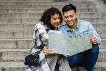 Smiling Couple Reading a Map While Sitting on Stone Steps
