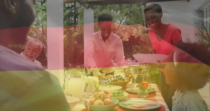 Animation of flag of germany over african american family eating dinner together