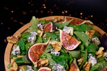 Whole and cut figs with blue cheese, nuts and arugula on a black background. Spicy taste. Mediterranean cuisine.