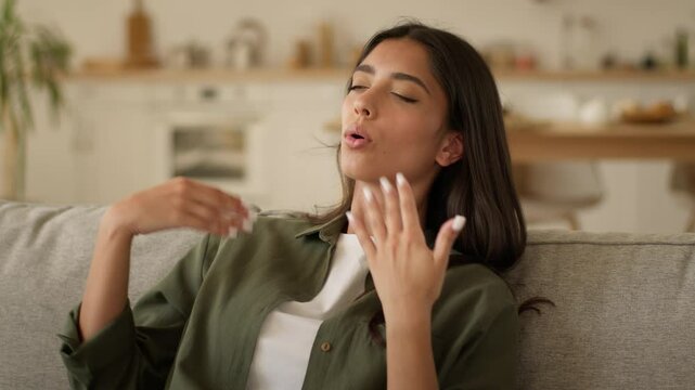 Upset sad overheated Indian woman suffering at home wave hand refresh sweaty Arabian lady Muslim girl female high temperature problem sweat hot air conditioner broken climate control discomfort summer