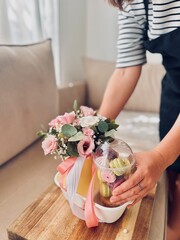 Woman’s hands giving a nice gift with flowers and macarons and crispy meringue