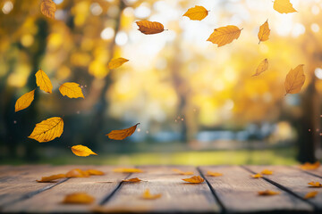 Wooden table with an autumn background and blurred golden-yellow bokeh light, with falling leaves in the air