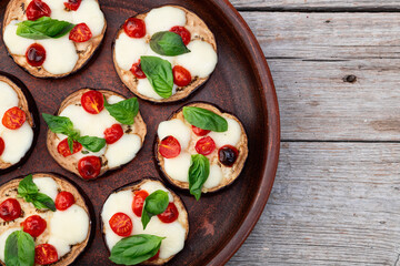 Italian mini pizza . Aubergine (eggplant ) with mozzarella cheese and basil . On rustic background