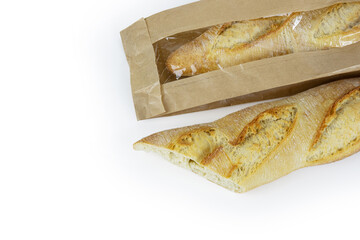 Two freshly baked baguettes, one wrapped in brown paper bag, Artisan French baguettes with crispy crusts in paper packaging. Isolated on a white background. Closeup. With clipping path.