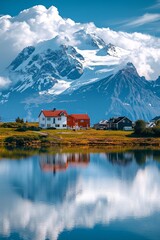 Fototapeta premium A small beautiful village in front of a snow capped mountain at a calm lake with reflection 