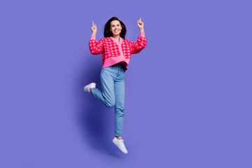 Full length photo of charming positive woman wear pink cardigan jumping high pointing up empty...