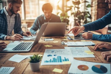 Fototapeta premium Business Meeting Around Wooden Table with Laptops and Charts
