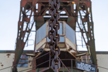 Closeup of a rusty chain on an old industrial harbor crane, highlighting the wear and age of the metal components