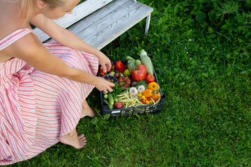 A girl sits on a bench after harvesting fresh vegetables