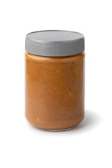 Glass jar with coarsely ground peanut butter close up isolated on white background