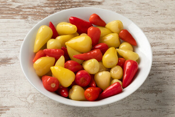 Bowl with pickled small red and yellow mexican hot peppers close up