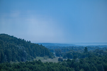 Rainy landscape of countryside forests and valley. Wet summer weather, rainy clouds in the sky, calm nature