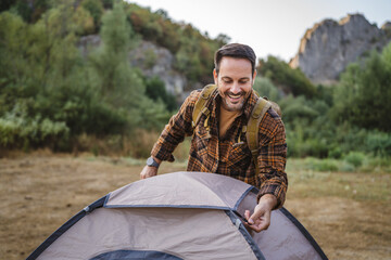 Adult man setting up a tent ready for camping trip at forest
