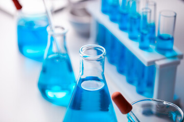 A collection of blue glass beakers and test tubes on a table. The blue color of the beakers and test tubes gives a sense of calmness and serenity