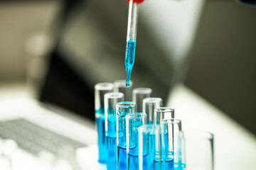 A person is pouring blue liquid into a series of test tubes. Concept of scientific experimentation and precision