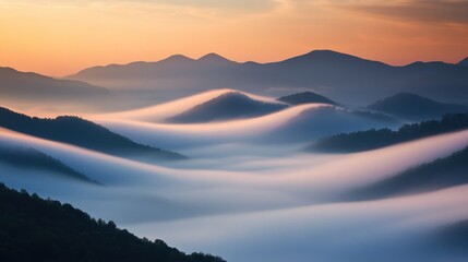 Fototapeta premium Serene landscape of rolling hills shrouded in mist during sunset.