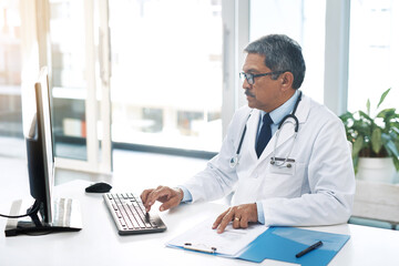 Mature man, doctor and office on computer with file for patient records, report and schedule. Male...
