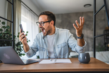 Frustrated angry adult man on yell on mobile phone at home