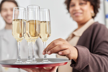 Close up of smiling Black woman taking champagne glass off tray during opening ceremony, focus on hand in foreground, copy space