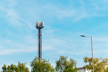 Tall Communication Tower Rises Against Backdrop of Clear Blue Skies and Leafy Trees