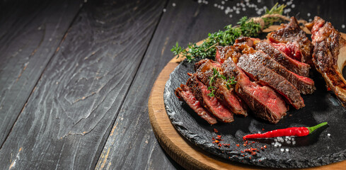 sliced rib eye Tomahawk beef veal steak on a dark background. top view. copy space for text