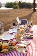 Picnic table set with various foods in a park.