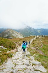 Hike on a rocky trail in the mountains with a misty sky.