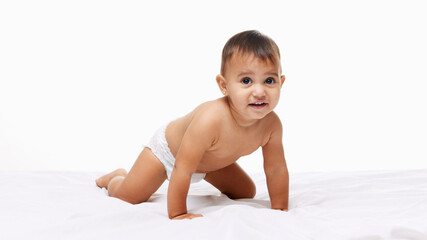 Little baby girl toddler in diaper crawling cheerfully on bed isolated on white studio background. Exploring and playing. Concept of childhood, parenthood, care