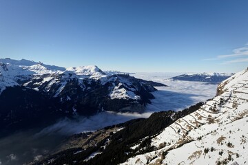 Mountain landscape with a sea of clouds covering the valley between the snowy landscape