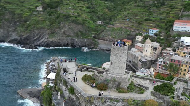 people on top of Doria Castle in Vernazza village with tranquil sea view and green mounts in Italy