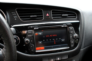 Monitor on dashboard of car in FM receiver. Controlling volume in car. Modern car multimedia. Detail of the car interior. 