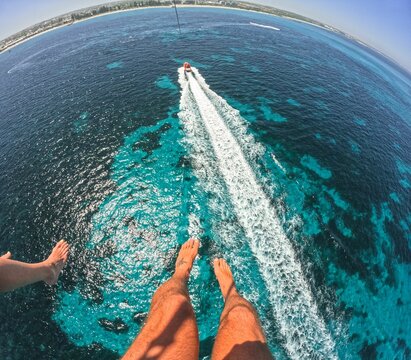 View of parasailing adventure over clear blue ocean water with a boat speeding below
