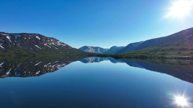 Drone tranquil view of Otta river on a sunny day surrounded by mountains with reflection in water