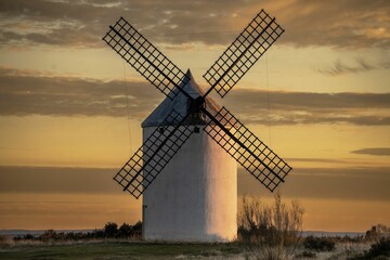 Fototapeta premium A picturesque windmill set against a stunning sunset sky in a rural landscape