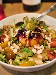 Gourmet salad with fried cheese ball and berry sauce.