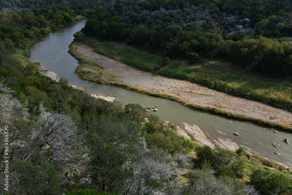 Sticker Aerial view of a winding river through a lush green forest.