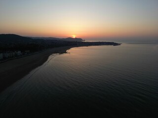 Aerial view of a coastal town at sunset with calm waters.