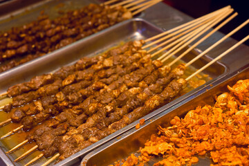 Delicious grilled Asian seafood skewers served on a platter at a bustling street food market during the evening hours