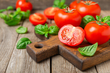 Fresh cherry tomatoes and fresh green basil on a textured background. Tomato sauce. Vegan. Ingredients for salad. Organic food. Place for text. Copy space.