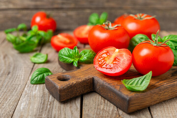 Fresh cherry tomatoes and fresh green basil on a textured background. Tomato sauce. Vegan. Ingredients for salad. Organic food. Place for text. Copy space.