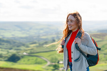 Adventurous Woman Hiking Through Lush Green Hills Under a Bright Sky During a Sunny Afternoon