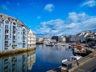 Fototapeta premium Norway with colorful buildings and a clear blue sky reflecting on the water.