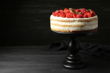 Tasty sponge cake with fresh berries and mint on dark gray wooden table, space for text