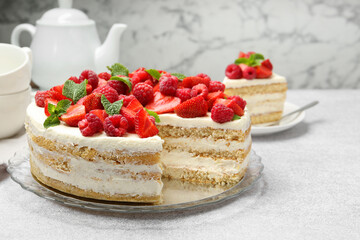 Tasty sponge cake with fresh berries and mint on light gray table, closeup